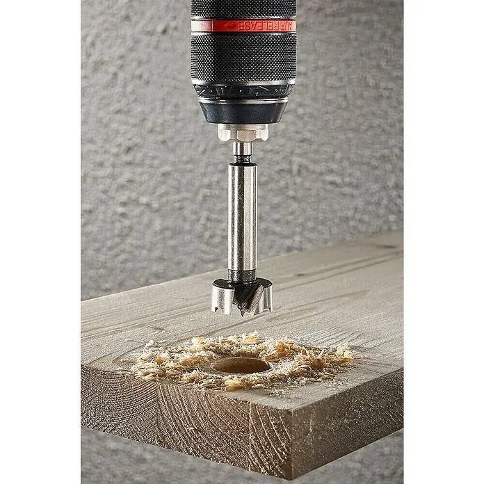 Wolfcraft Forstnerbohrer - Durchmesser Bohrer: 20 mm - Ein Forstnerbohrer bohrt ein Loch in ein Holzbrett, Späne liegen um das Loch herum.