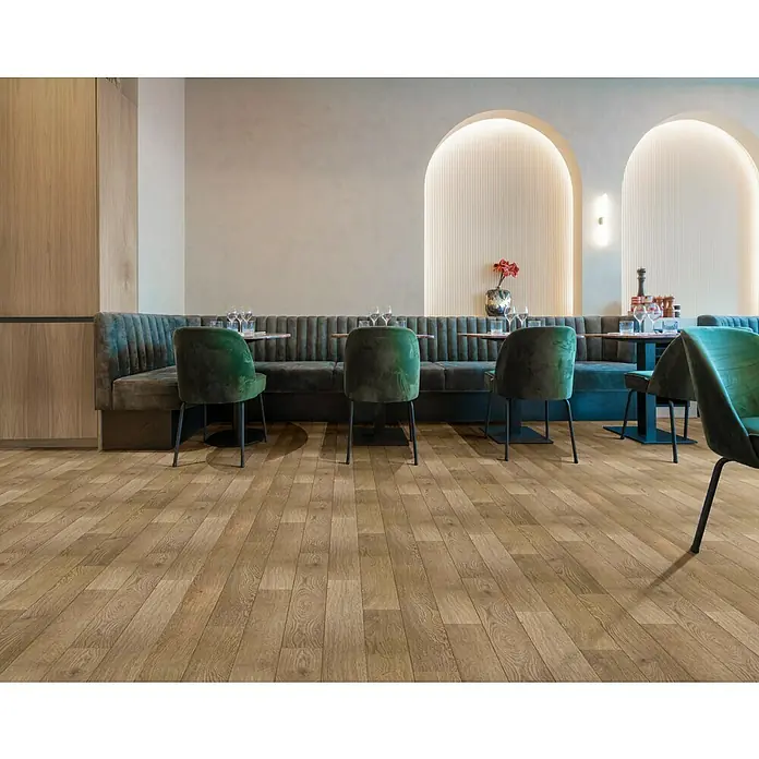 Beauflor PVC-Boden Meterware Titan - Holzoptik, Breite: 400 cm, Braun - Einladender Restaurantbereich mit grünen Samtstühlen und Holzboden, der eine warme und stilvolle Atmosphäre schafft.