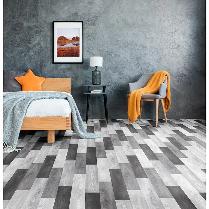 Beauflor PVC-Boden Meterware Plaza - 400 cm, Keyline, Grau/Schwarz - Gemütliches Schlafzimmer mit Holzbett, grauem Tagesdecke und Akzenten in Orange. Abstraktes Bild und dekorative Lampe auf dem Nachttisch.