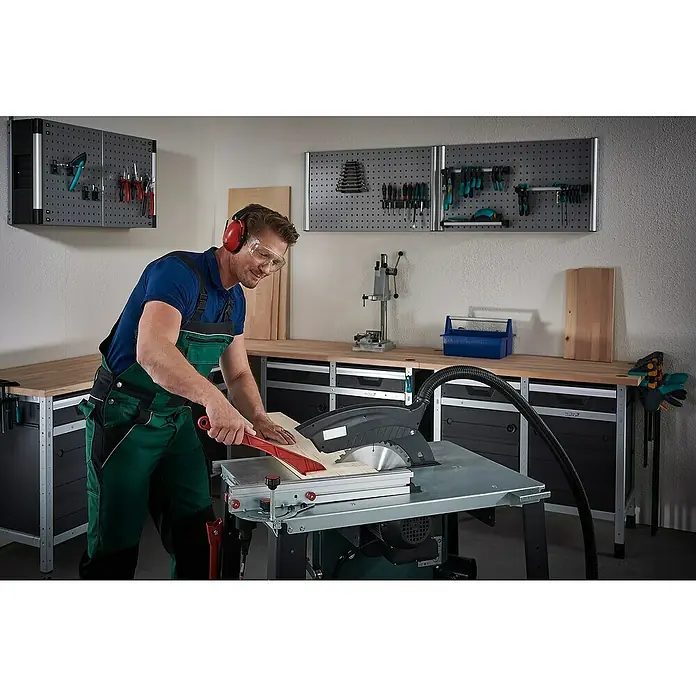 Wolfcraft Kreissägeblatt Serie lila - 315 mm, Bohrung: 30 mm, Anzahl Zähne: 48 Stk. - Ein Handwerker in Arbeitskleidung bedient eine Tischkreissäge in einer Werkstatt.