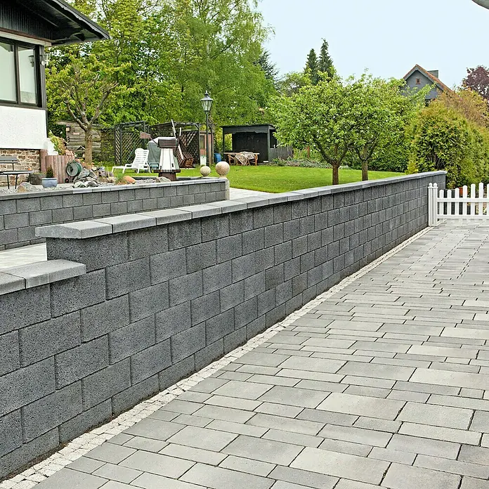EHL Planomur Mauerstein Normalstein - Anthrazit, 50 x 25 x 20 cm, Beton - Die graue Steinmauer und der gepflasterte Weg präsentieren eine harmonische Gartengestaltung. Ideal für langlebige Außenbereiche.
