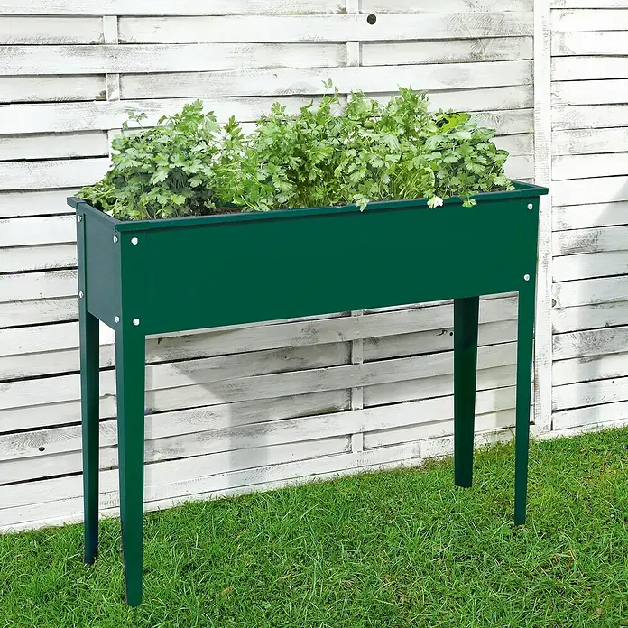 Floraworld Hochbeet - 80 x 100 x 30 cm, Metall, Grün - Ein erhöhter, grüner Pflanzkasten mit Kräutern steht vor einem weißen Holzzaun. Praktisch für Garten, Terrasse oder Balkon.