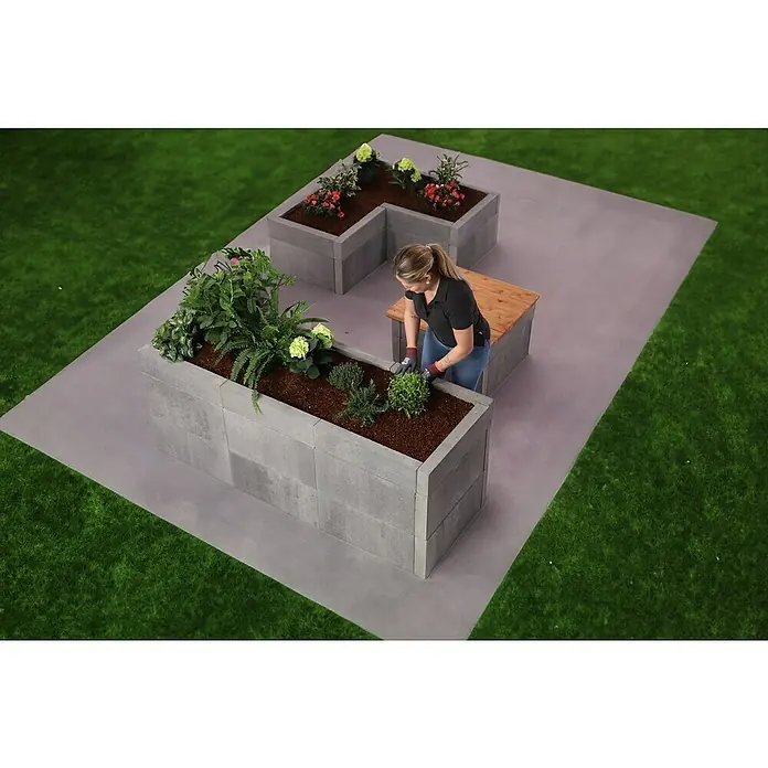 EHL Creaform Loungetisch - 72,5 x 72,5 x 48 cm, Steingrau, Beton - Erhöhtes Gartenbeet aus Betonsteinen, bepflanzt mit Blumen und Pflanzen, mit einer Frau, die darin arbeitet.