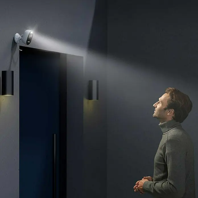 Reolink Überwachungskamera LUMUS SERIES E430 - 2560 x 1440 Pixel, IP65, Außen - Überwachungskamera mit Flutlicht beleuchtet einen Mann. Ideal für die Sicherheit im Außenbereich.
