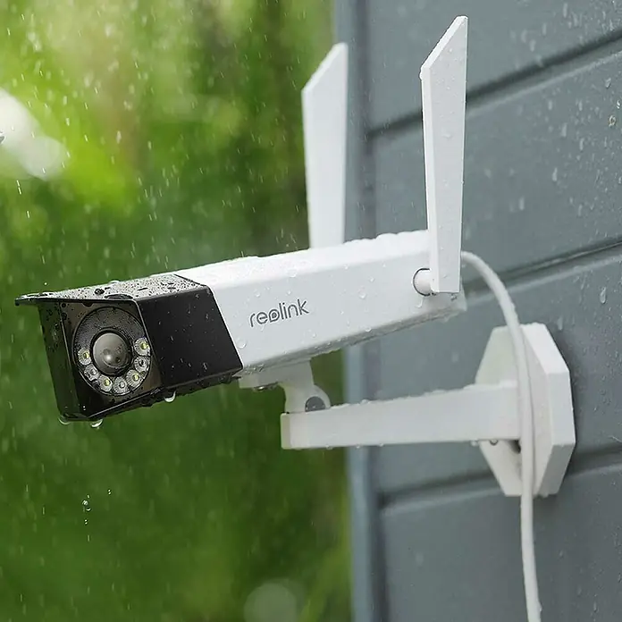 Reolink Überwachungskamera DUO SERIES W730 - 4.608 x 1.728 Pixel, IP66, Außen - Nahaufnahme einer wetterfesten Reolink Überwachungskamera mit Antennen, die an einer grauen Wand im Regen montiert ist.