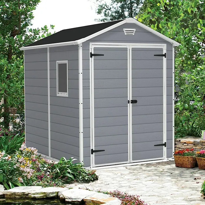 Keter Caseta de jardín Manor 6x8 - Medidas ext. (An x Pr): 185,8 x 236,8 cm, Gris Claro/Blanco, Plástico, Área: 3,9 m² - Cobertizo de jardín gris con puertas dobles, ventana pequeña y techo negro, rodeado de exuberante vegetación, ideal para herramientas.