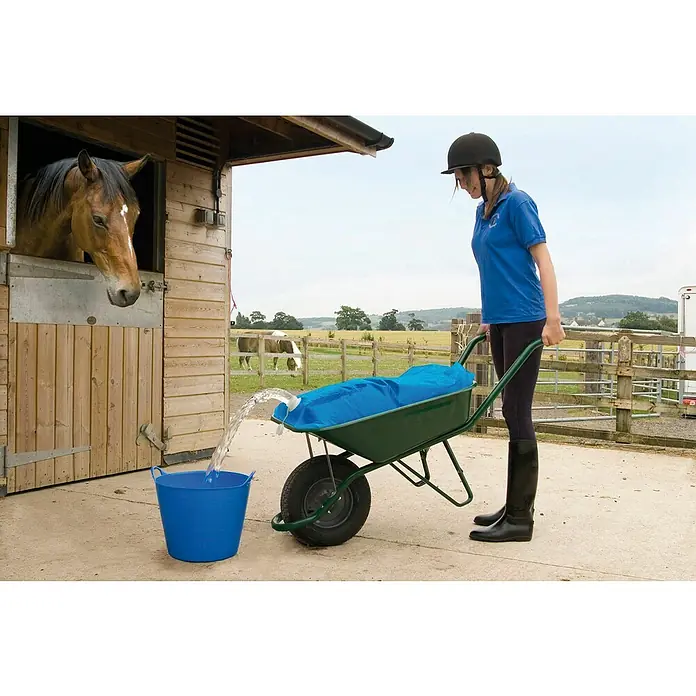 Kerbl Wasserbehälter für Schubkarren H2GOBAG - L x B x H: 33 x 24,5 x 6 cm, Fassungsvermögen: 80 l - Eine Frau befüllt mit einem Wasserwagen eine blaue Tonne, während ein Pferd aus einem Stallfenster schaut. Nützliches Produkt für die Pferdeversorgung.