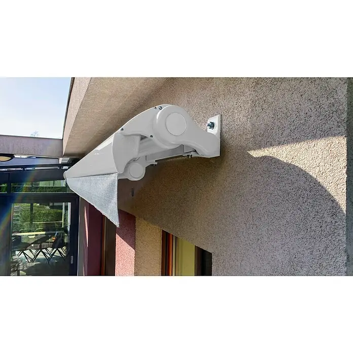 SM Hülsenmarkise REC-196 - Hellgrau, Farbe Gestell: Verkehrsweiß, Breite: 2,5 m, Ausfall: 2 m - Nahaufnahme einer weißen Markise, die an der Wand eines Hauses befestigt ist und Schutz vor der Sonne bietet. Die Markise ist halb ausgefahren.