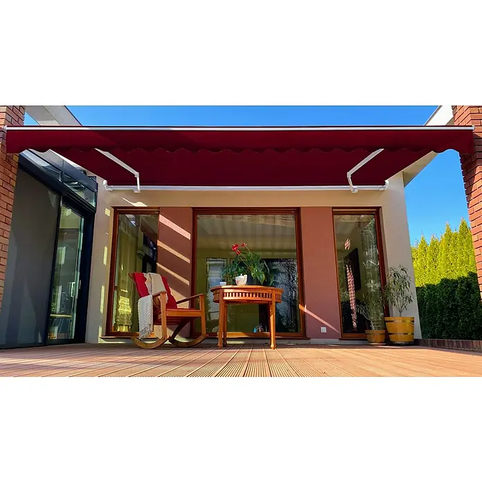 SM Gelenkarmmarkise T-407/11 - Rot, Farbe Gestell: Verkehrsweiß, Breite: 2,5 m, Ausfall: 2 m - Ein rotes Gelenkarmmarkise schützt eine Terrasse mit Holzdeck, einem Tisch, einem Schaukelstuhl und Pflanzen vor der Sonne.