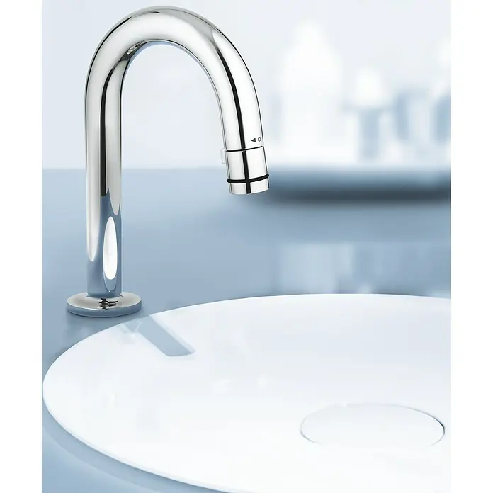 Grohe Kaltwasser-Standventil Universal - C-Auslauf, Chrom, Glänzend - Ein moderner, verchromter Wasserhahn auf einem weißen Waschbecken, der durch sein elegantes Design und seine hohe Funktionalität besticht.