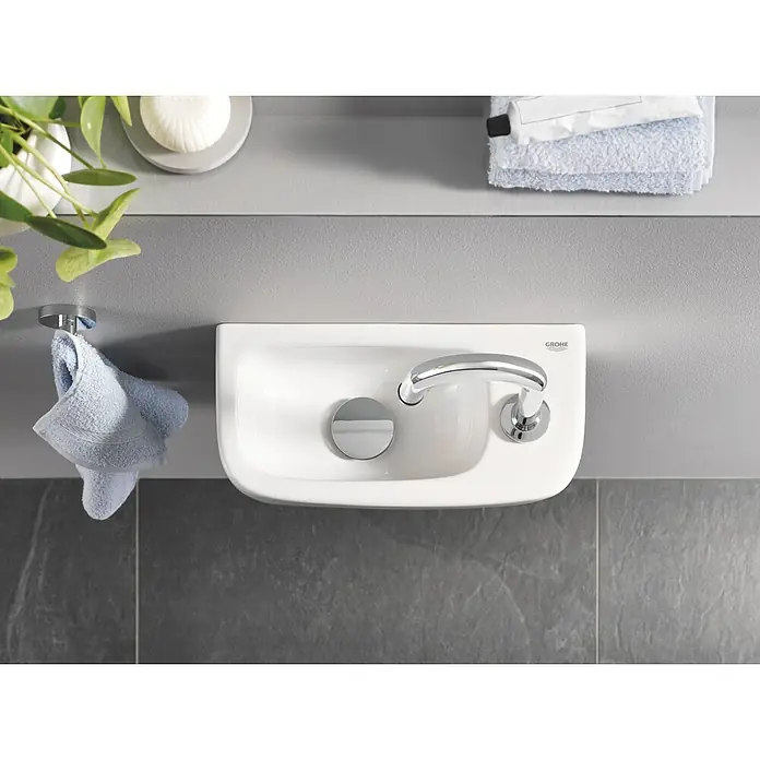 Grohe Kaltwasser-Standventil Universal - C-Auslauf, Chrom, Glänzend - Nahaufnahme eines weißen Grohe Waschbeckens mit Armatur und Handtuchhalter im modernen Badezimmer.