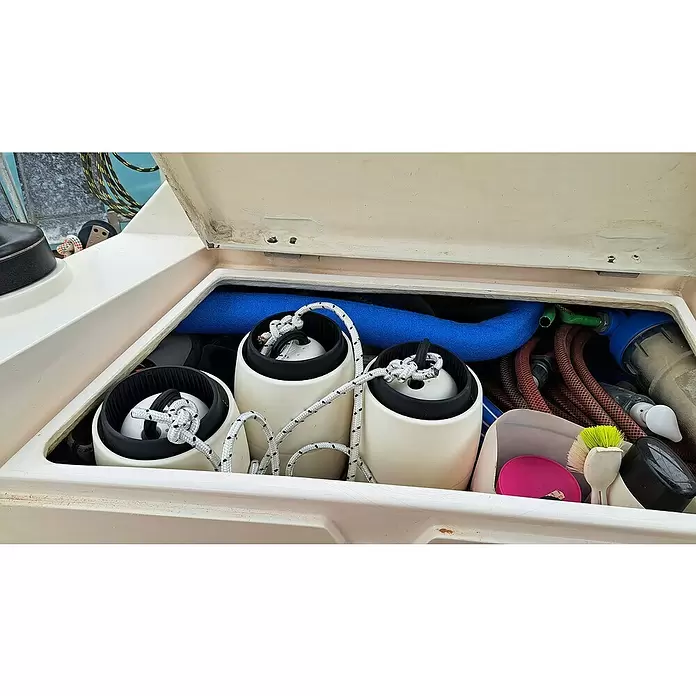Defensa multifender Zebra - Diámetro: 16,5 cm, Ajustable: 25 cm - 62 cm, Blanco/Negro - Tres defensas de barco blancas y negras con cabos blancos enrollados, guardadas ordenadamente en un compartimento de barco abierto.