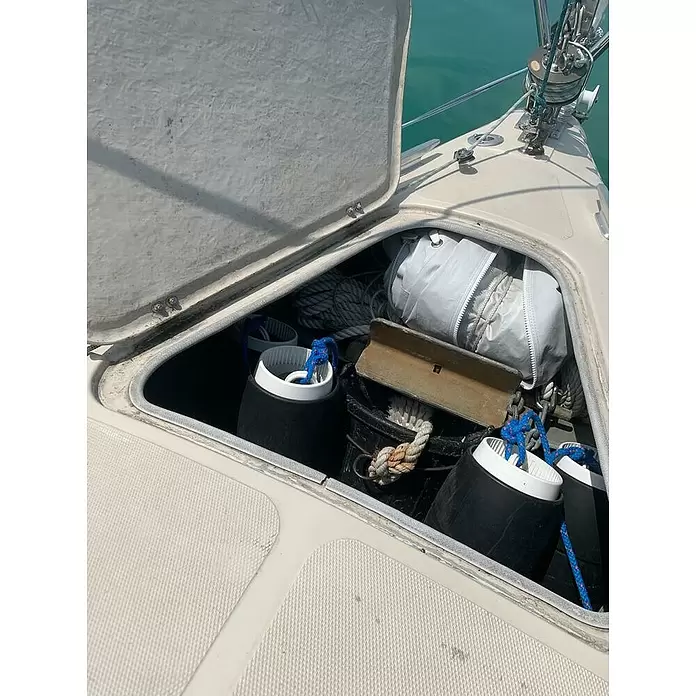 Defensa multifender Zebra - Diámetro: 16,5 cm, Ajustable: 25 cm - 62 cm, Blanco/Negro - Tambucho de proa abierto de barco mostrando equipo marino organizado: cabos enrollados, defensas, bolsa de vela y cepillo. La cubierta es blanquecina.