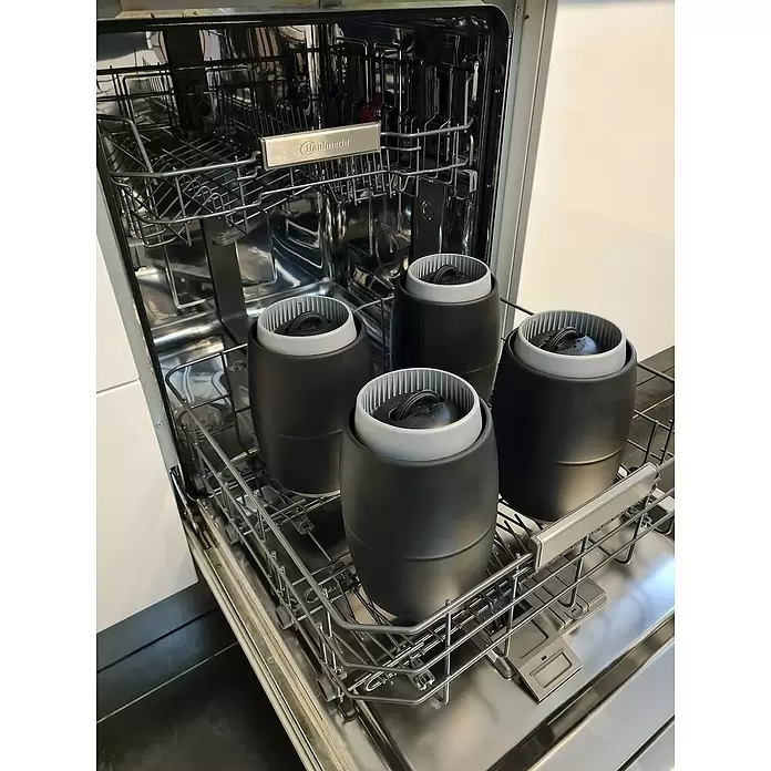 Defensa multifender Zebra - Diámetro: 16,5 cm, Ajustable: 25 cm - 62 cm, Blanco/Negro - Cuatro recipientes cilíndricos negros con inserciones gris claro, colocados ordenadamente en la cesta inferior de un lavavajillas.
