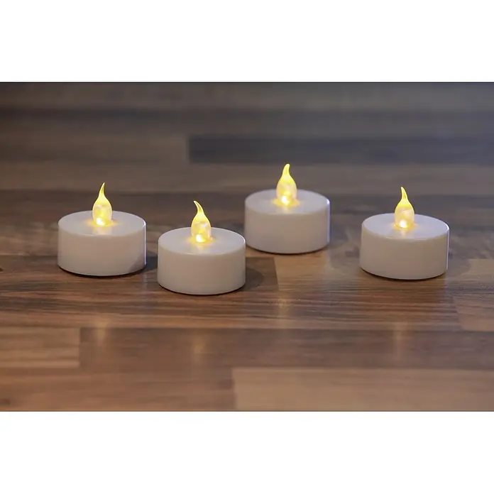 LED-Teelicht Nele - Ø x H: 3,8 x 3,5 cm, Weiß, 24 Stk. - Vier LED-Teelichter mit warmweißem Licht auf einem Holztisch. Stimmungsvolle Dekoration für Zuhause und Veranstaltungen.