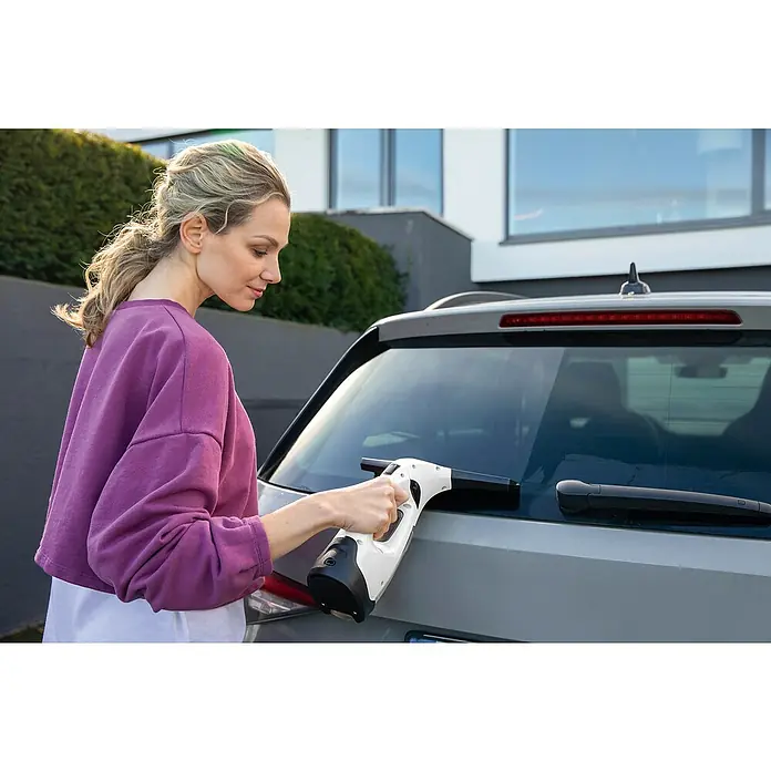 Kärcher Limpiadora de cristales de batería WV 2 Plus N - 1 batería, Volumen de recipiente: 0,1 l - Mujer que usa un limpiacristales inalámbrico WV para limpiar la ventana trasera de un coche.