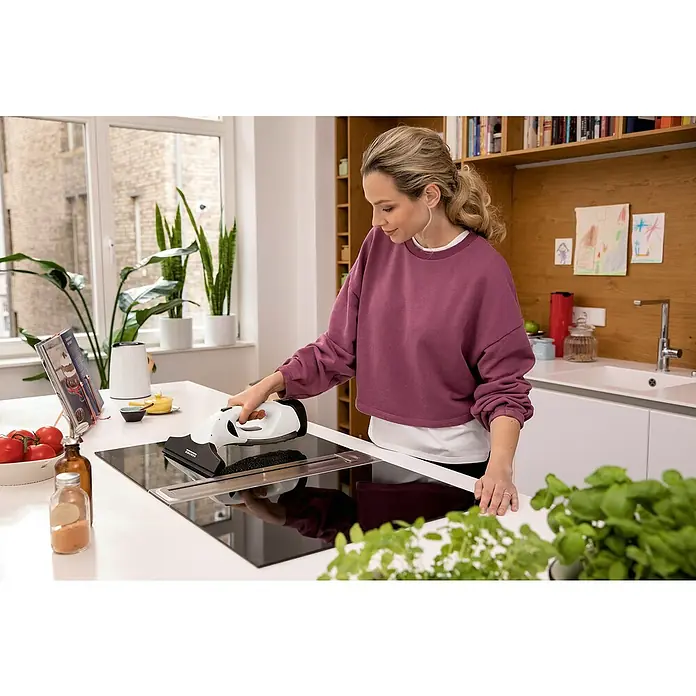 Kärcher Limpiadora de cristales de batería WV 2 Plus N - 1 batería, Volumen de recipiente: 0,1 l - Mujer limpia una placa de cocina con un aspirador de ventanas Kärcher. El Kärcher garantiza una limpieza higiénica y sin rayas.