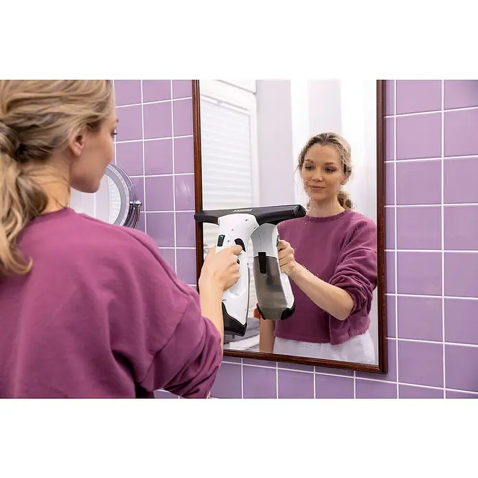 Kärcher Limpiadora de cristales de batería WV 2 Plus N - 1 batería, Volumen de recipiente: 0,1 l - Mujer limpiando espejo con aspirador de ventanas. Este innovador aspirador de ventanas garantiza una limpieza sin rayas.