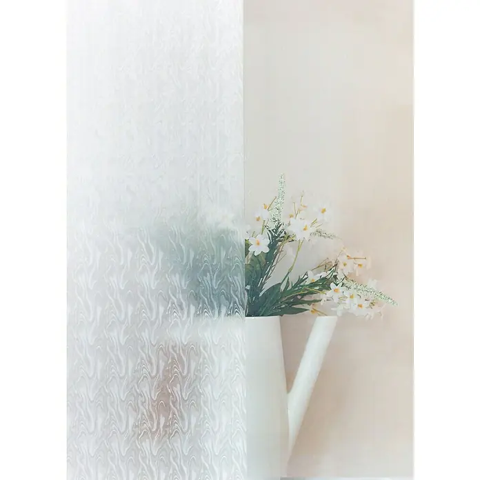 D-c-fix Glasfolie Smoke - 200 x 45 cm, Transluzent, Selbstklebend - Das Bild zeigt dekorative Fensterfolie mit einem Muster, kombiniert mit einer Vase mit weißen Blumen, die für eine elegante Raumgestaltung sorgt.