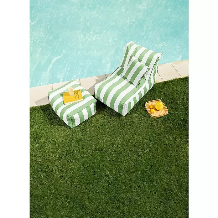 Sitting Point Sitzsack Santorin Rock - 100 x 65 x 65 cm, Grün/Weiß, 100 % Polypropylen - Grün-weiß gestreifte Outdoor-Sitzsackliege und Hocker auf Rasen am Pool, mit Buch und Getränk auf dem Hocker.