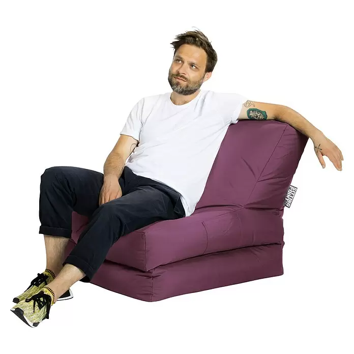 Sitting Point Sitzsack Twist Scuba - 90 x 70 x 80 cm, Aubergine, 100 % Polyester/100 % Polyvinylchlorid - Ein Mann sitzt bequem auf einem lila, faltbaren Bodenkissen und demonstriert dessen Nutzung als Loungesessel.