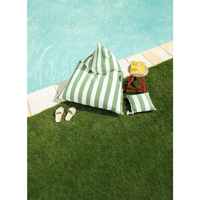 Sitting Point Sitzsack Santorin Calypso - 110 x 115 x 90 cm, Grün/Weiß, 100 % Polypropylen - Ein grüner, gestreifter Sitzsack neben einem Pool, ergänzt durch einen Hocker mit Buch und einem Getränk für entspannte Stunden.