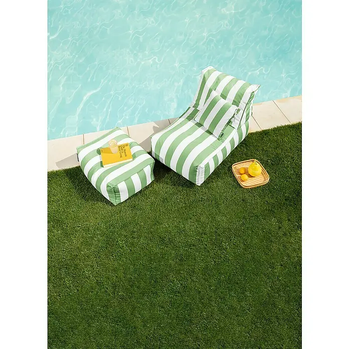 Sitting Point Sitzhocker Santorin Roll - 65 x 55 x 35 cm, Grün/Weiß, 100 % Polypropylen - Eine grüne, gestreifte Sitzgruppe mit Sessel und Hocker steht auf dem Rasen neben einem Pool, perfekt für entspannte Stunden im Freien.