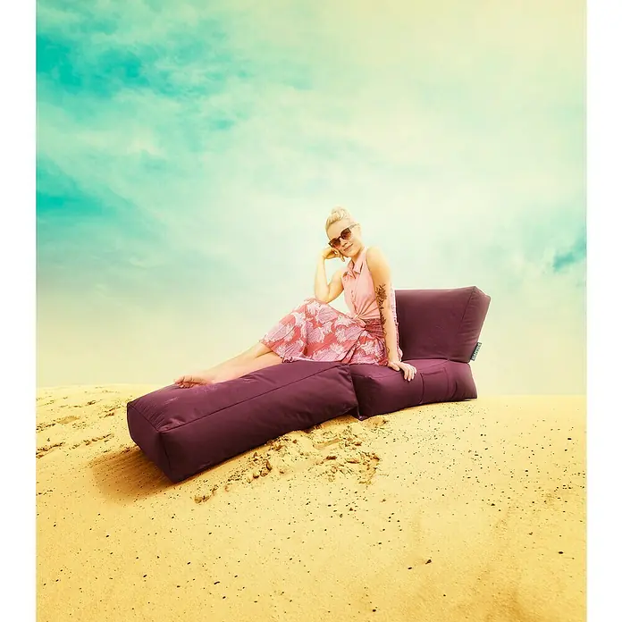 Sitting Point Sitzsack Twist Scuba - 90 x 70 x 80 cm, Aubergine, 100 % Polyester/100 % Polyvinylchlorid - Frau entspannt auf einem lilafarbenen Outdoor-Sitzsack-Liegestuhl in der Wüste, ideal zum Entspannen und Genießen der Natur.