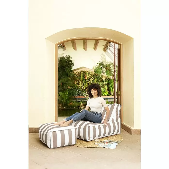 Sitting Point Sitzsack Santorin Rock - 100 x 65 x 65 cm, Taupe/Weiß, 100 % Polypropylen - Gestreifter weiß-taupe Sitzsack und Hocker-Set, eine Person entspannt in Gartenumgebung.
