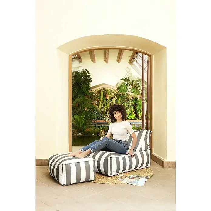 Sitting Point Sitzhocker Santorin Roll - 65 x 55 x 35 cm, Taupe/Weiß, 100 % Polypropylen - Eine Frau sitzt entspannt auf einem gestreiften Sitzsack mit Fußhocker, der zum Entspannen einlädt. Bequeme Sitzgelegenheiten für den Innen- und Außenbereich.