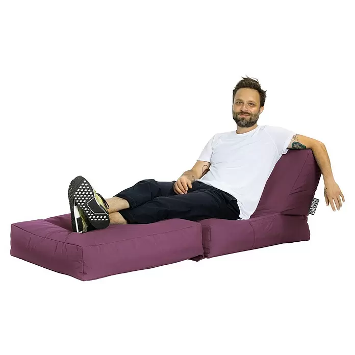 Sitting Point Sitzsack Twist Scuba - 90 x 70 x 80 cm, Aubergine, 100 % Polyester/100 % Polyvinylchlorid - Mann entspannt auf einem violetten modularen Sitzsack mit hochgelegten Füßen, der sein bequemes und anpassungsfähiges Design zeigt.