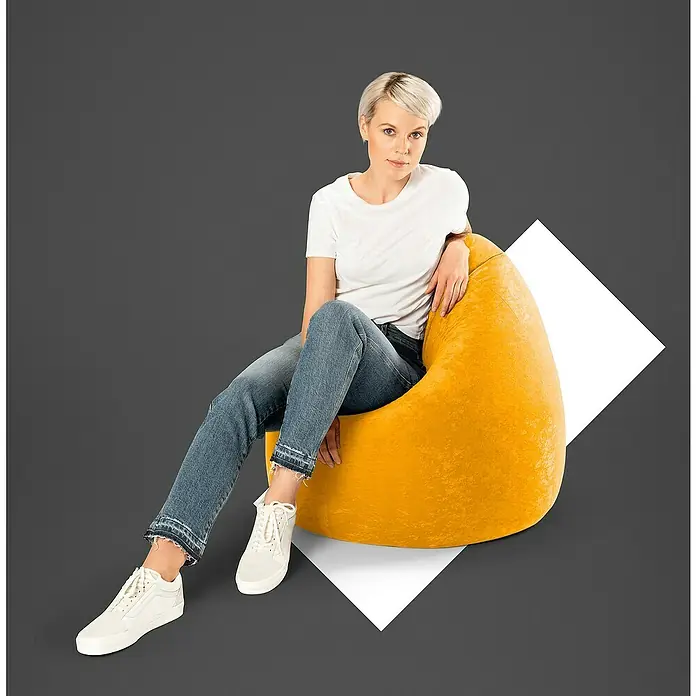 Sitting Point Sitzsack Beanbag Easy - XL, Gelb, 100 % Polyester - Eine Frau sitzt auf einem leuchtend gelben Sitzsack vor einem grauen Hintergrund mit einem weißen Quadrat, das das Produkt hervorhebt.