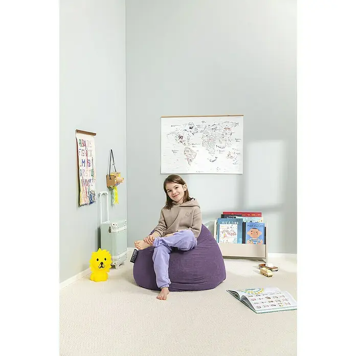 Sitting Point Sitzsack Beanbag Easy - L, Lila, 100 % Polyester - Ein Mädchen sitzt auf einem lilafarbenen Sitzsack in einem Kinderzimmer mit einer Weltkarte und Spielzeug. Der Sitzsack ist das zentrale Element des Bildes.