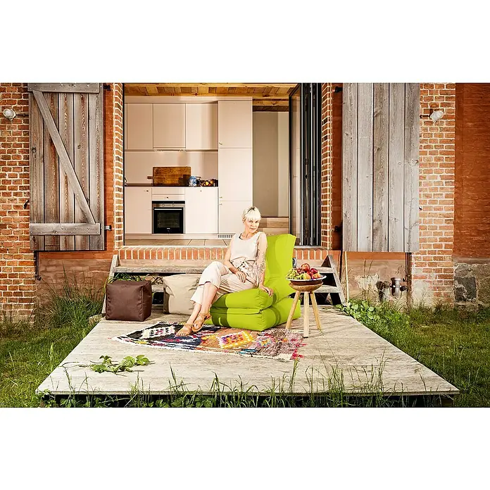 Sitting Point Sitzsack Twist Scuba90 x 70 x 80 cm, Grün, 100 % Polyester/100 % Polyvinylchlorid - Frau entspannt auf einem grünen Sitzsack im Freien. Das moderne Möbelstück bietet Komfort und Stil für den Außenbereich.