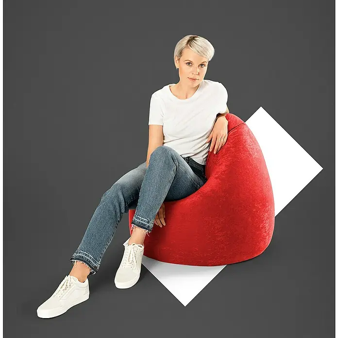 Sitting Point Sitzsack Beanbag EasyXL, Rot, 100 % Polyester - Eine Frau sitzt lässig auf einem roten Sitzsack mit weißem T-Shirt, Jeans und Turnschuhen vor grauem Hintergrund.