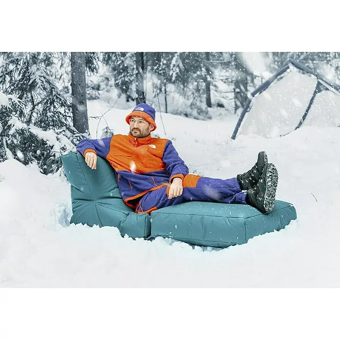 Sitting Point Sitzsack Twist Scuba - 90 x 70 x 80 cm, Petrol, 100 % Polyester/100 % Polyvinylchlorid - Mann entspannt auf einem blauen modulierbaren Outdoor-Sofa im Schnee, gekleidet in The North Face, mit einer Zeltkulisse.