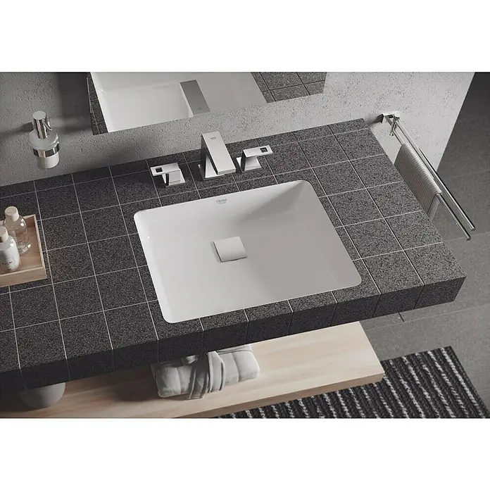 Grohe Essentials Ersatz-Seifenspender - Chrom, Glänzend - Elegantes Badezimmer-Waschbecken von Grohe, eingebettet in eine stilvolle, dunkle Arbeitsplatte. Die Armaturen ergänzen das moderne Design perfekt.