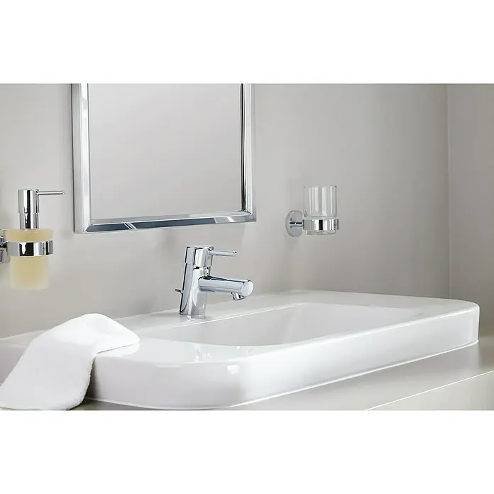 Grohe Essentials Zahnputzbecher - Mit Halterung, Chrom, Glänzend - Nahaufnahme eines modernen Badezimmers mit einem Waschbecken, Armatur, Spiegel, Seifenspender und einem Glas für Zahnbürsten, alles in Chrom gehalten.
