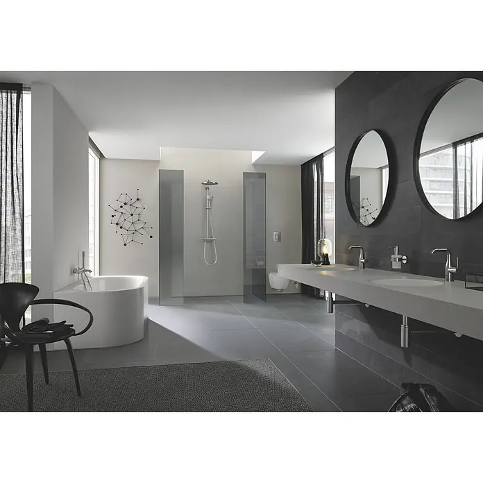 Grohe Essence New Waschtischarmatur M-Size - Mit Zugstange, Supersteel, Glänzend - Ein modernes Badezimmer mit einer freistehenden Badewanne und einem Doppelwaschtisch mit runden Spiegeln für einen stilvollen Look.