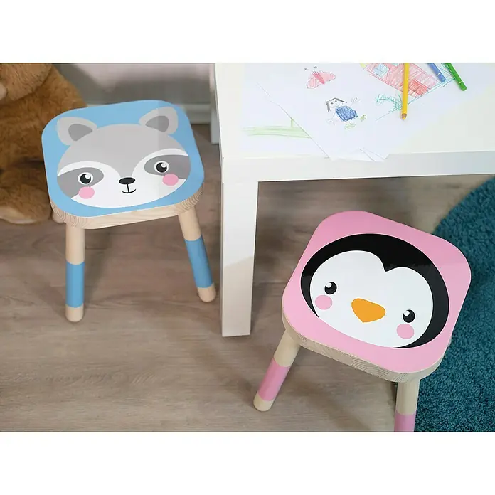 D-c-fix Klebefolie Uni Lack - 200 x 67,5 cm, Schwarz, Selbstklebend - Kinderhocker mit Tiermotiven. Ein blauer Hocker mit Waschbärgesicht und ein rosa Hocker mit Pinguin neben einem Tisch mit Malzeug.