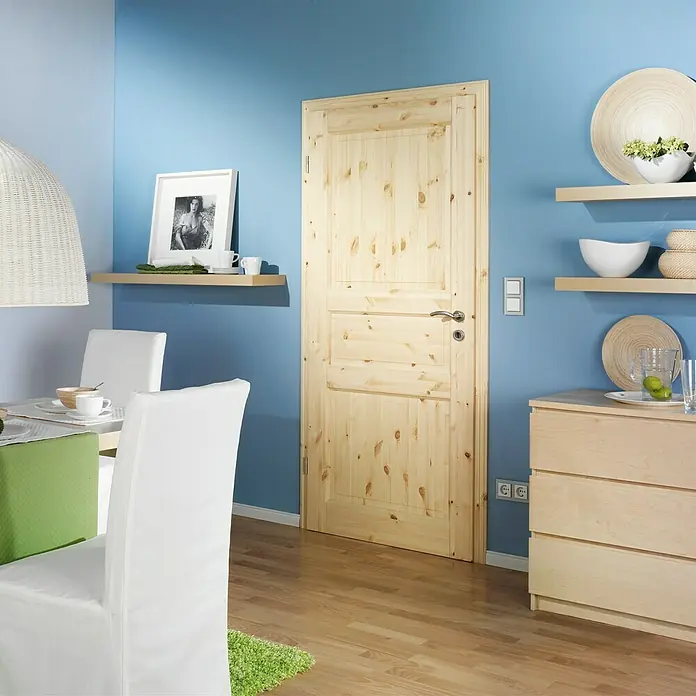 Kilsgaard Landhaustür 02/03 - 610 x 1.985 mm, DIN Anschlag: Links, Kiefer natur - Zimmer mit einer Holztür, die sich in die Wand einfügt. Die Holztür fügt sich gut in die blaue Wand des Raumes ein.