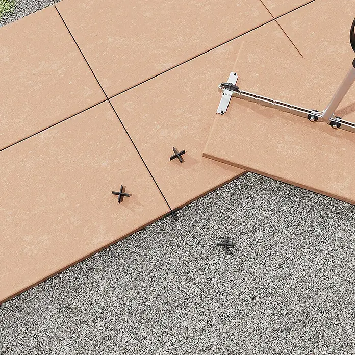 Langfit Fugenkreuz - 100 Stk., Fugenbreite 6 mm - Die Bild zeigt einen Terrassenbau mit Feinsteinzeugplatten, Nivelliersystem und Kreuzfugen. Die Verlegung erfolgt auf einem Kiesbett.