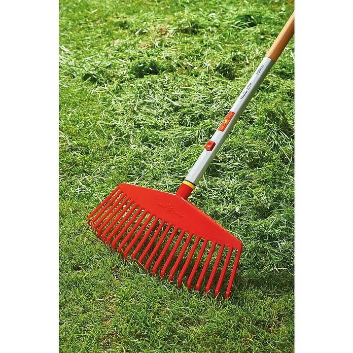 Wolf-Garten Multi-Star Fächerbesen Ui-M - Arbeitsbreite: 42 cm - Ein roter Wolf Garten Laubbesen mit einem Multi-Star Stiel liegt auf frisch gemähtem Gras. Ideal für die Gartenarbeit!