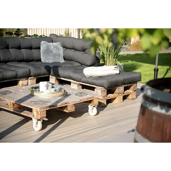 Elephant Terrassenbau-Set WPC strongWood - Walnuss/Vintage, Deckfläche pro Paket: 25 m² - Ein Palettensofa mit anthrazitfarbenen Polstern und ein Palettentisch mit Rollen sorgen für ein gemütliches Ambiente im Freien.