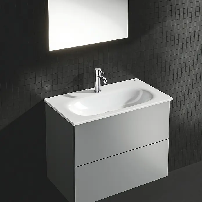 Grohe Essence New Waschtischarmatur S-Size - Mit Zugstange, Chrom, Glänzend - Badezimmermöbel mit Waschbecken und Spiegel in modernem Design. Der Unterschrank ist grau mit zwei Schubladen, das Becken weiß.