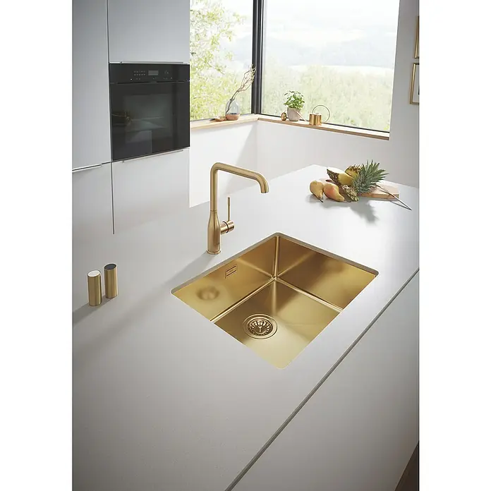 Grohe Essence Spültischarmatur - U-Auslauf, Cool Sunrise, Matt - Küchenspüle aus Gold mit Wasserhahn. Das Spülbecken ist quadratisch und eingebaut, die Arbeitsplatte ist in Weiß gehalten.