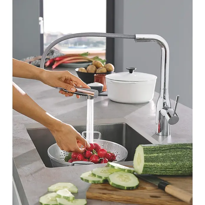Grohe Essence Spültischarmatur - L-Auslauf, Chrom, Glänzend - Eine moderne Küchenarmatur mit Ausziehbrause wird verwendet, um frisches Gemüse in einem stilvollen Küchendesign zu waschen.