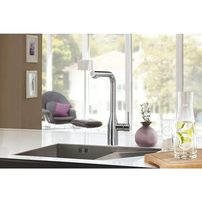 Grohe Essence Spültischarmatur - L-Auslauf, Chrom, Glänzend - Elegante Küchenarmatur von Grohe, glänzend und modern, mit passendem Wasserkrug und Gläsern auf einer hellen Arbeitsfläche.