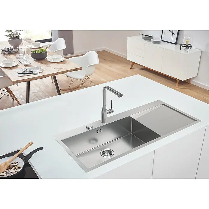 Grohe Essence Spültischarmatur - L-Auslauf, Supersteel, Matt - Hochwinkelaufnahme einer modernen Küche mit einem Edelstahlspülbecken und einer Armatur. Der Fokus liegt auf dem eleganten Design und der Funktionalität.