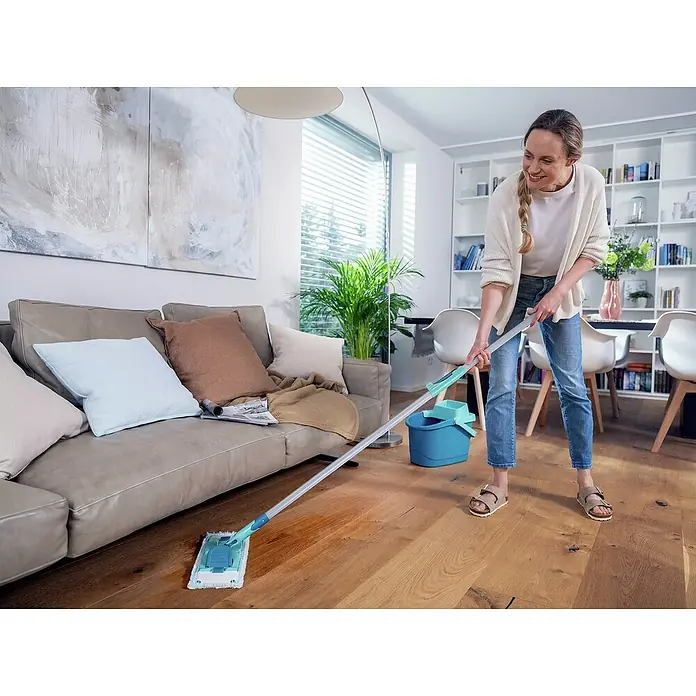 Leifheit Power Clean Bodenwischer M Teleskopstiel - 33 cm, Materialspezifizierung: Mikrofaser - Eine Frau wischt mit einem Bodenwischer den Holzboden in einem hellen Wohnzimmer, während ein blauer Eimer daneben steht.
